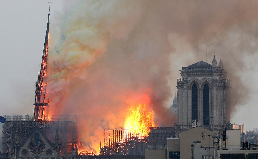 Flames rise from Notre Dame cathedral as it burns in Paris, Monday, April 15, 2019. Massive plumes of yellow-brown smoke are filling the air above Notre Dame Cathedral and ash is falling on tourists and others around the island that marks the center of Paris.