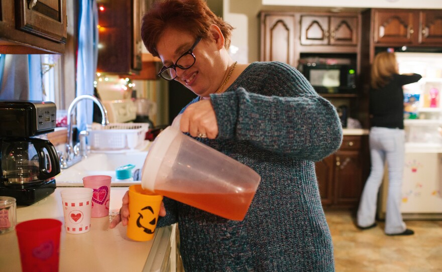 Pauline helps pour juice for dinner at her group home.