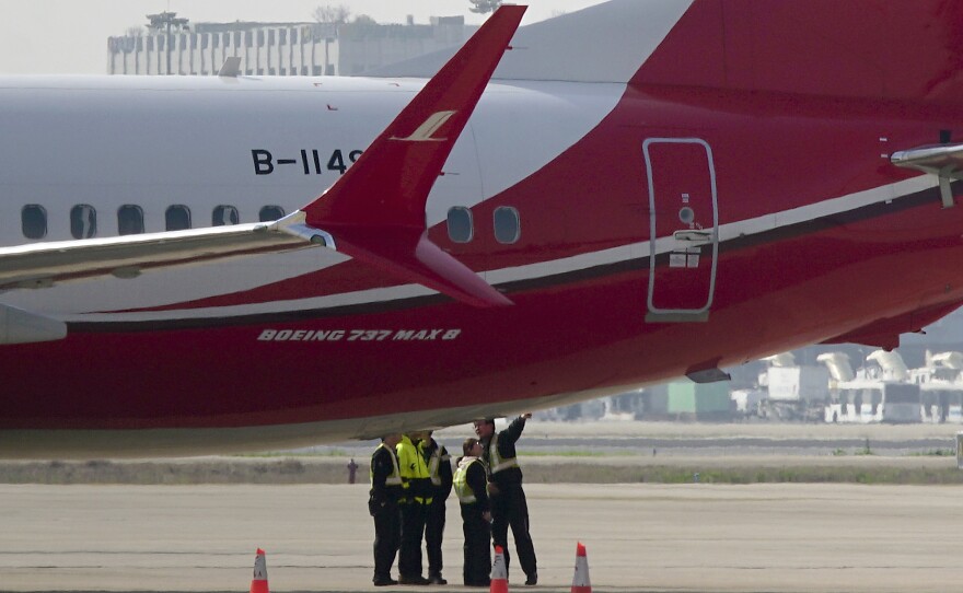 Members of the ground crew chat near a Boeing 737 Max 8 plane operated by Shanghai Airlines and parked on the tarmac at Shanghai Hongqiao International Airport in China. On Monday, the Civil Aviation Administration of China ordered all the country's airlines to ground their Boeing 737 Max 8 planes after Sunday's fatal crash of the same model plane in Ethiopia.