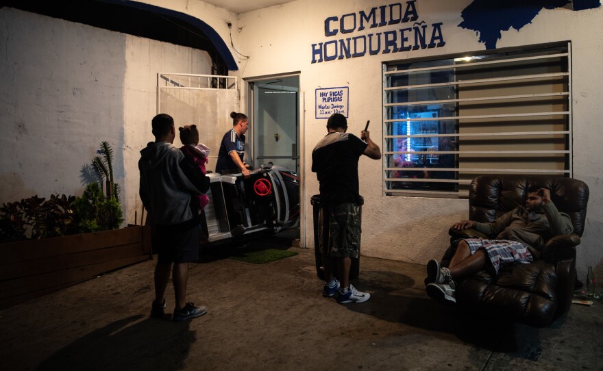 Cristian Aguilar carries his half-brother Jaden's toy car into the restaurant Honduras 504, owned by his father José Aguilar. Cooking up traditional food, it has served the Honduran diaspora community in Tijuana since 2015.