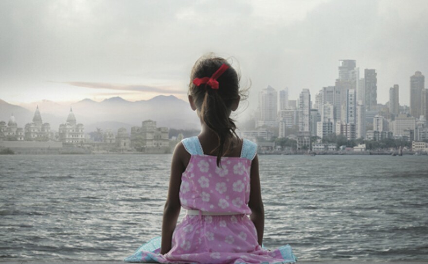 Promotional photo of a young girl sitting by the water looking at the city skyline, for the film "The World Before Her."