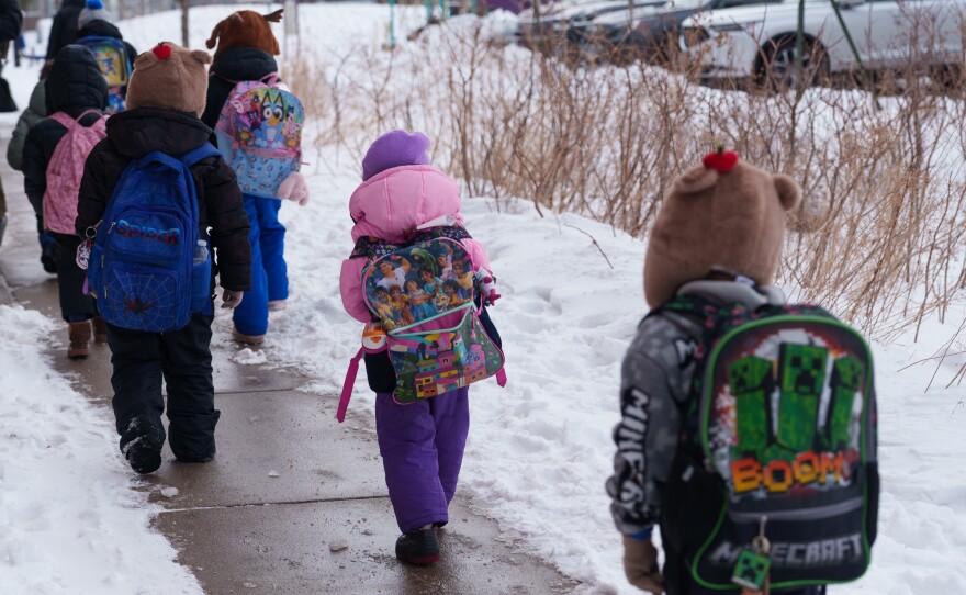 Students walk from the bus to their elementary school in St. Paul, Minn., on March 18. For many students, it was the first week back after nearly two months of online learning.