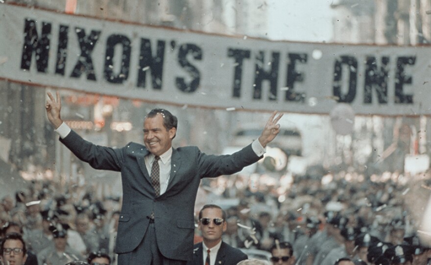 "Nixon's The One" campaign slogan banner hangs behind the candidate during a campaign rally.