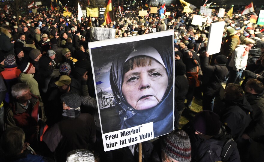 A protester in Dresden, Germany, holds a poster Monday showing Chancellor Angela Merkel wearing a headscarf during a rally organized by PEGIDA, a group that is against what it calls the "Islamization of Europe."