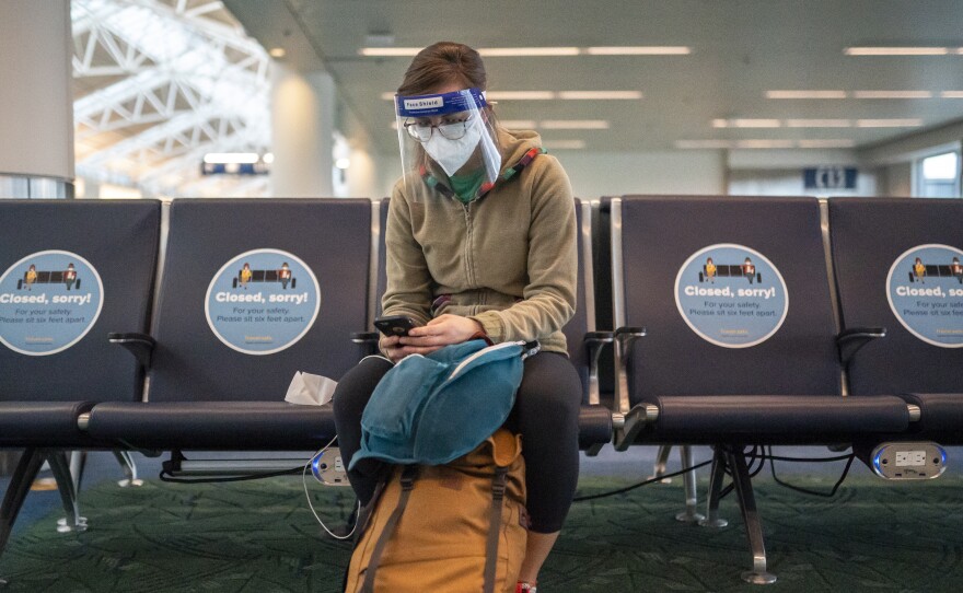 A traveler waits for a flight at Portland International Airport last week in Oregon. Public health experts say it's important that those who traveled or gathered with others are especially careful over the next two weeks.