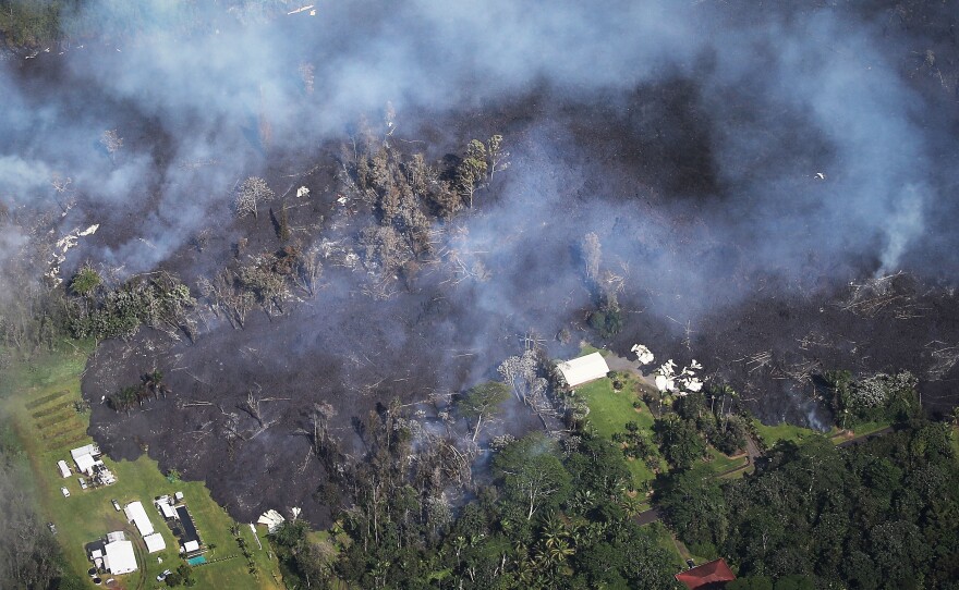 Lava from volcanic fissures slowly advances and overtakes structures and trees in the Leilani Estates neighborhood on Sunday. At least 26 homes have been destroyed by lava.