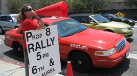 Sara Beth Brooks stands on a street corner in Hillcrest promoting tonight's rally and march. 