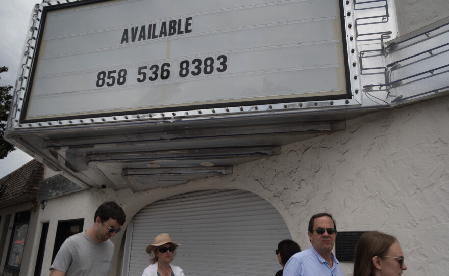 People walk under the marquee of the Carlsbad Theater on State Street on July 20, 2026. Lettering on the sign says "Available. 858 536 8383"