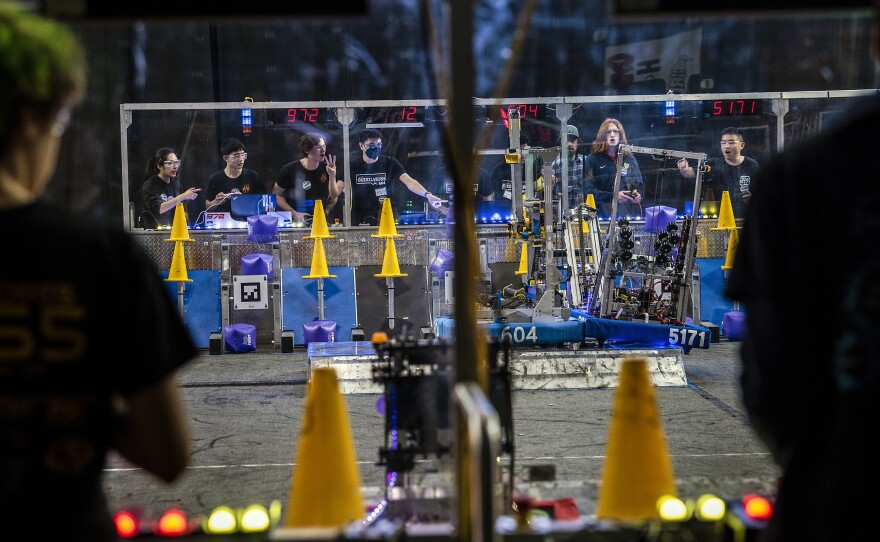 <strong>The finals of the 2023 Silicon Valley Regional:</strong> After rushing throughout the match to place cones on poles and cubes in slots to score, the teams earn a large point bonus at the end by cooperating with their alliance partners to balance all three robots on an unstable, tilting platform.