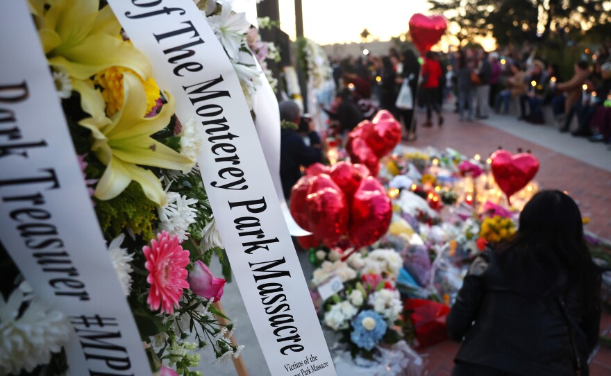 People gather at a memorial for the victims of a mass shooting over the weekend at a ballroom dance studio in Monterey Park, Calif.