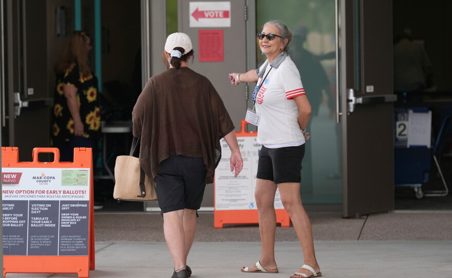 A poll worker assists an Arizona voter at a polling location in Phoenix as people cast their ballots on Tuesday.