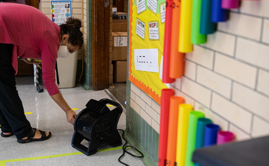 Quesada turns on a fan outside her classroom door. She spends most of her time before class on COVID-19 precautions. She has spent nearly $600 of her own money on air purifiers and fans to improve the ventilation in her classroom.
