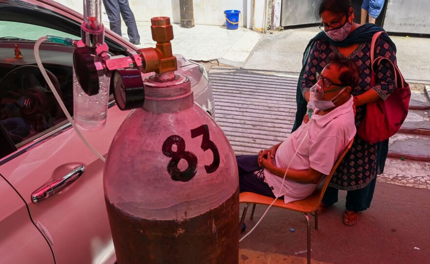 A COVID-19 patient breathes with the help of oxygen at a tent installed along a roadside on Wednesday in Ghaziabad.