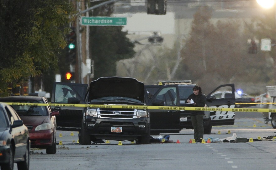 An investigator looks at a Black SUV that was involved in a police shootout with suspects in San Bernardino, Calif. Dec. 3, 2015.