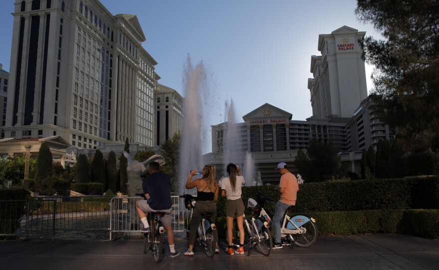 Cyclists stop to look at the fountains at the Caesars Palace hotel and casino on Tuesday on the Las Vegas Strip, which is empty of its normal crowds because of the COVID-19 pandemic.