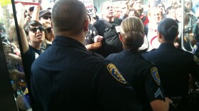Police keep protesters outside of Cal State Trustees headquarters in Long Beach, Calif.