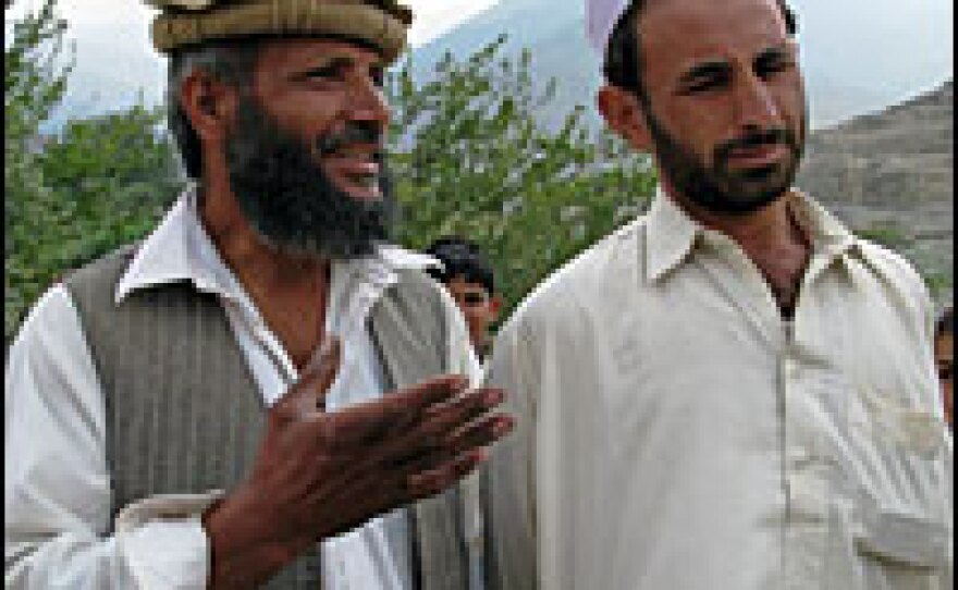 Afghan farmer Noor Aziz, left, stands next to a Pakistani refugee in Daridam village on the Afghan side of the border. Behind the mountains in the distance lies Pakistan.