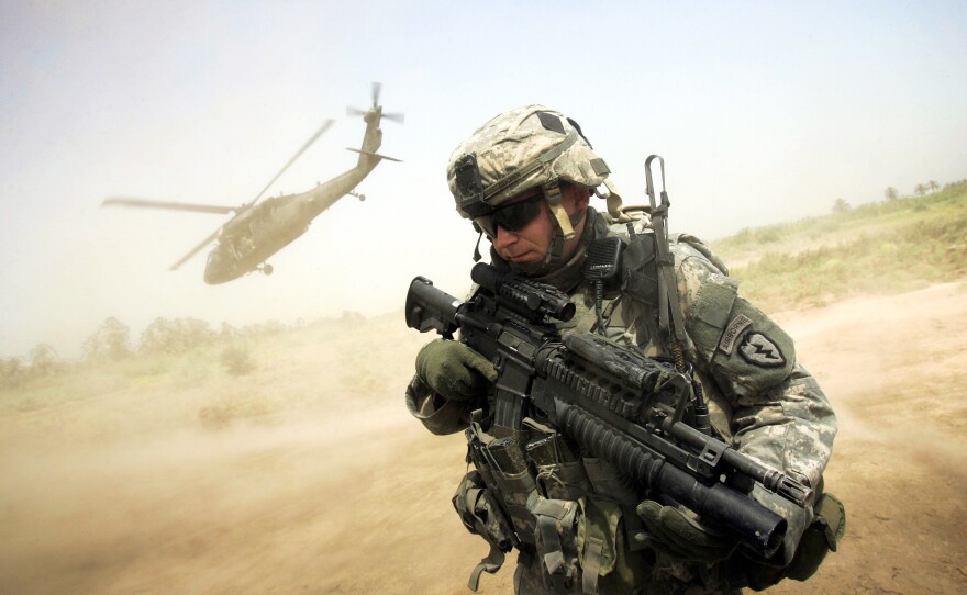 A U.S. soldier turns his back to the helicopter carrying Maj. Gen. Rick Lynch, the U.S. commander in central Iraq, as the chopper takes off from a patrol base south of Baghdad, in 2007. A surge in U.S. troops that year changed the course of the war and helped stabilize Iraq, at least temporarily.