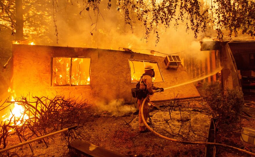 Firefighters battle flames at a burning apartment complex in Paradise, Calif., in November. State fire officials say power lines coming into contact with trees have sparked multiple Northern California wildfires in recent years. PG&E filed for bankruptcy Tuesday.