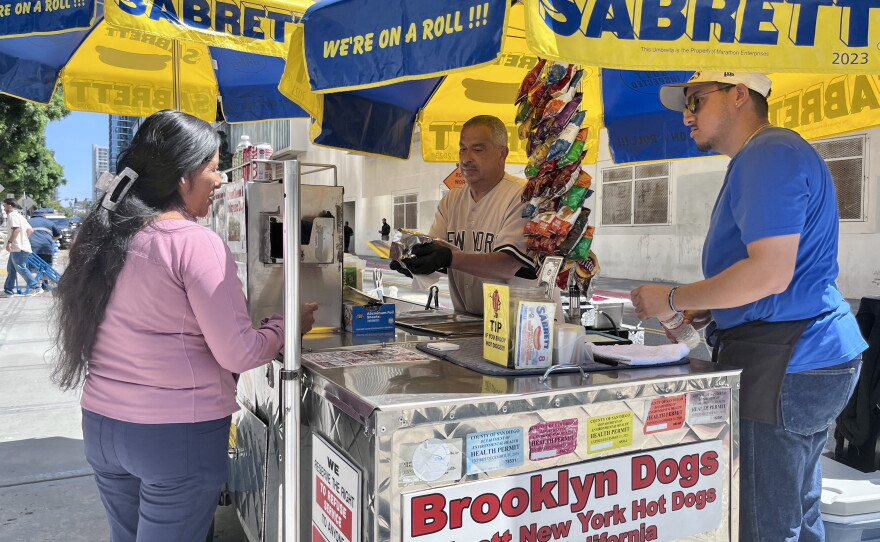 Pete Soto and his son sell hot dogs to customers from their Brooklyn Dogs street cart in downtown San Diego, July 7, 2026.