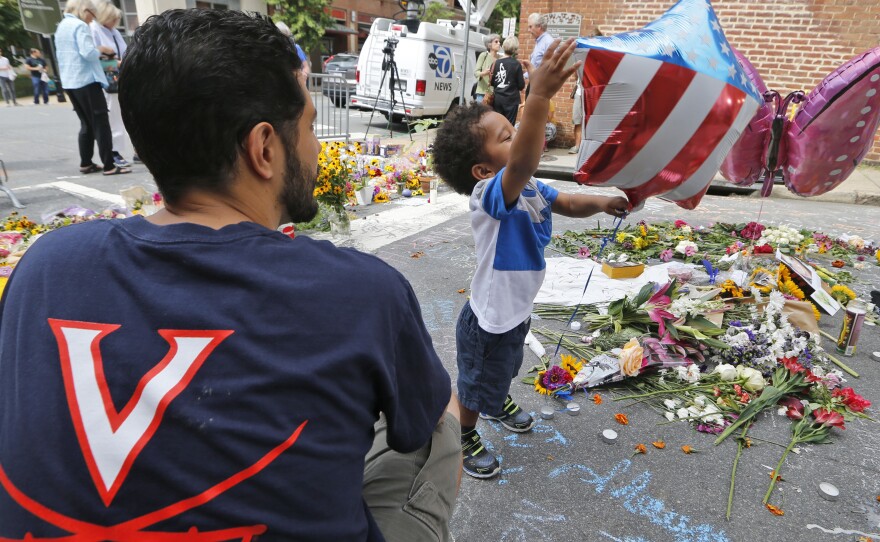 Pastor Daniel Xisto and his son Max, 2, look over a makeshift memorial on Monday for Heather Heyer, who was killed in a car attack on Saturday after a white nationalist rally in Charlottesville, Va. While many are calling the attack an act of domestic terrorism, U.S. federal law has no such specific criminal charge.