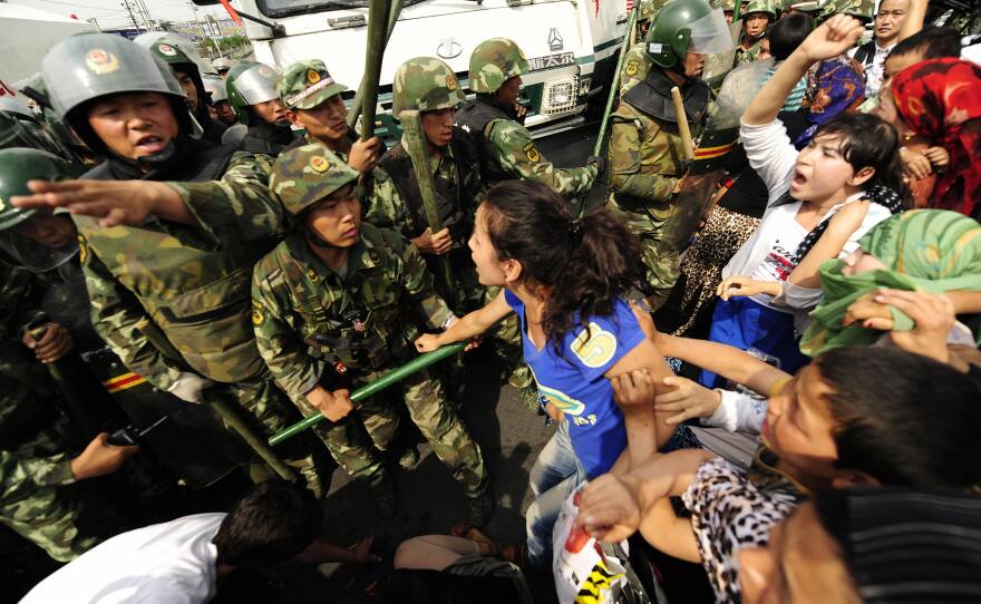 Ethnic Uighur women yell at Chinese riot police during a protest in Urumqi in China's far west Xinjiang region on July 7, 2009. Nearly 200 people were killed and more than 1,000 injured in riots throughout July 2009.
