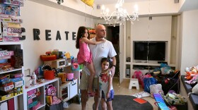 Ido Dan, an uncle to three children feared abducted by Hamas and taken to Gaza, stands for a portrait with his twin daughters. The remnants of their sixth birthday party, which took place the same day as the incursion, are still around the house.
