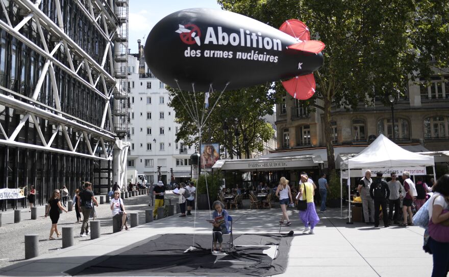 A woman sits underneath a balloon, carrying the logo of the International Campaign to Abolish Nuclear Weapons, in Paris on August 7, 2017. Activists were holding a four-day hunger strike calling for France to sign the ICAN-supported treaty to ban nuclear weapons. The group has now won the Nobel Peace Prize.