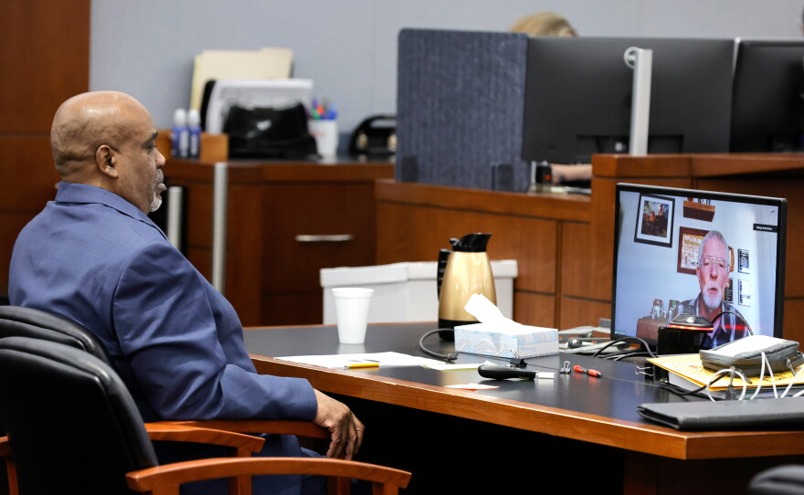 Duane Davis listens as Brent Becker, a retired Las Vegas Metro Police Department homicide detective, testifies by video feed during his murder trial, related to the 1996 killing of rapper Tupac Shakur, at Clark County District Court Regional Justice Center, Monday, Aug. 17, 2026, in Las Vegas.