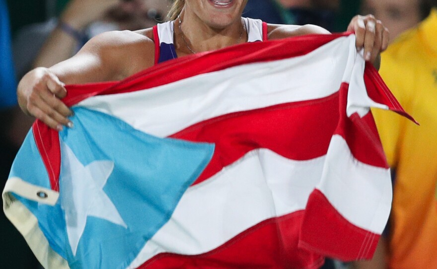Monica Puig of Puerto Rico celebrates holding her country's flag after winning the gold medal match in the women's tennis competition — Puerto Rico's first-ever Olympic gold medal.
