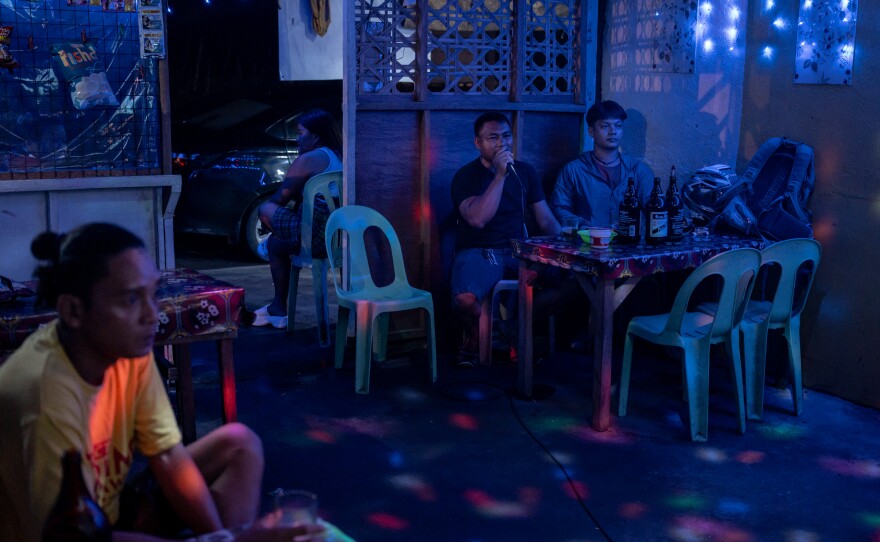 People sing karaoke on May 21, 2025, at a local bar near the main fish port complex in General Santos, the Philippines, where the clientele are mainly fishermen on their days off.