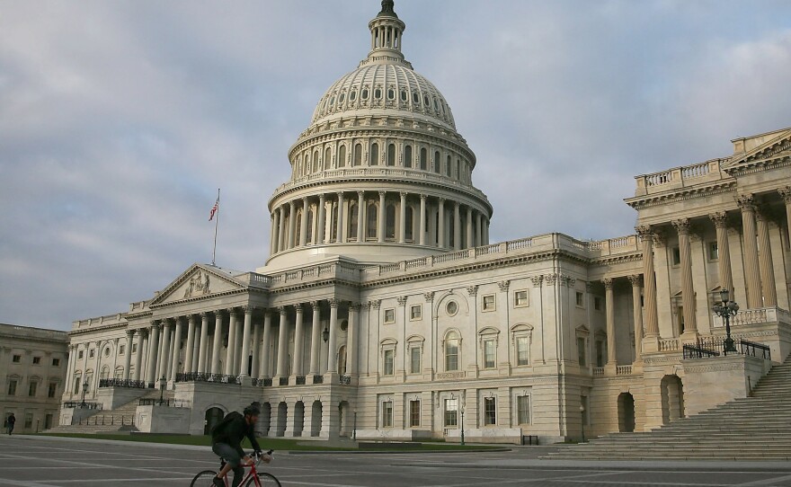 A biker rides past the U.S. Capitol on Monday. Lawmakers are negotiating over plans to raise the federal debt ceiling amid warnings that the government soon won't be able to pay its debts in full.