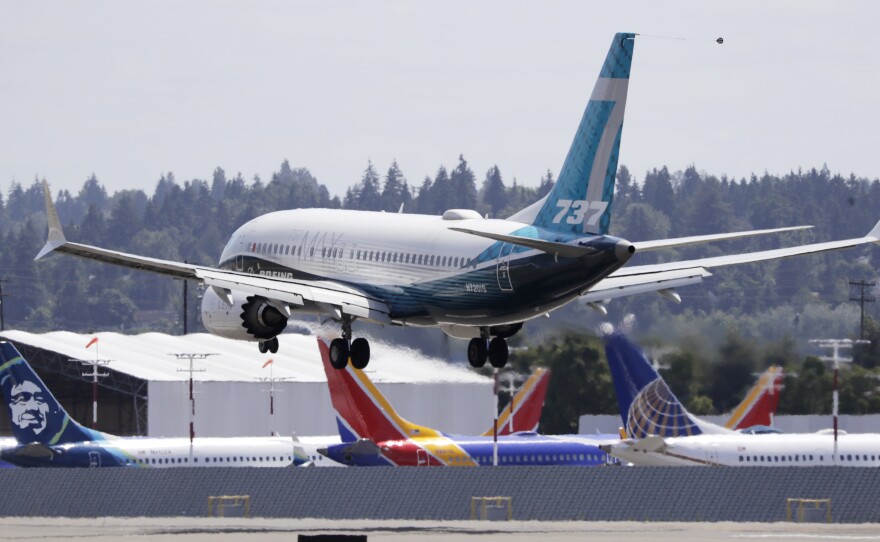 A Boeing 737 Max heads to a landing past grounded Max jets at Seattle's Boeing Field, following a test flight in June. It was the first of three days of re-certification test flights that mark a step toward returning the aircraft to passenger service.