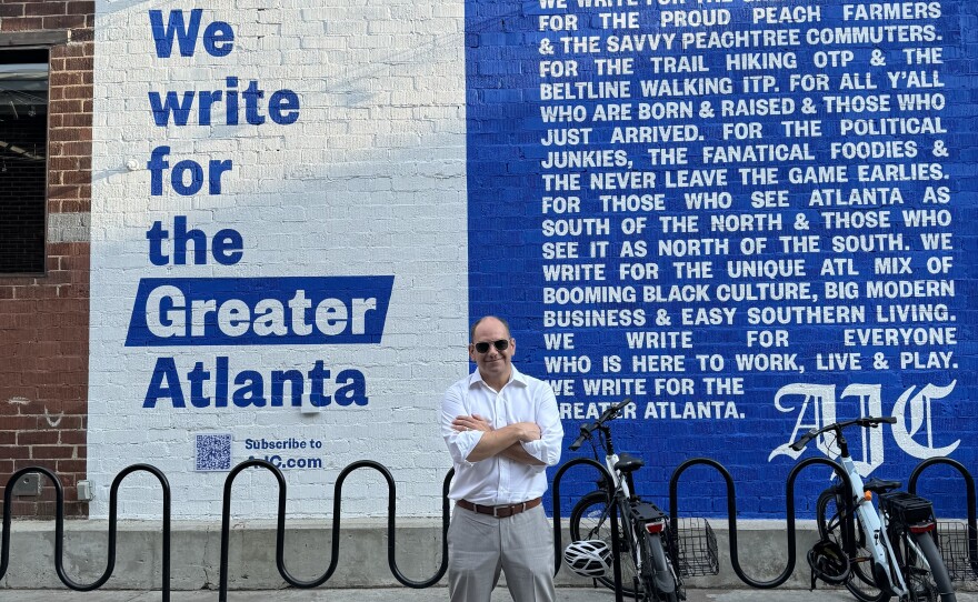 Andrew Morse, the publisher and president of The Atlanta Journal-Constitution, stands before a mural advertising the newspaper in 2024.