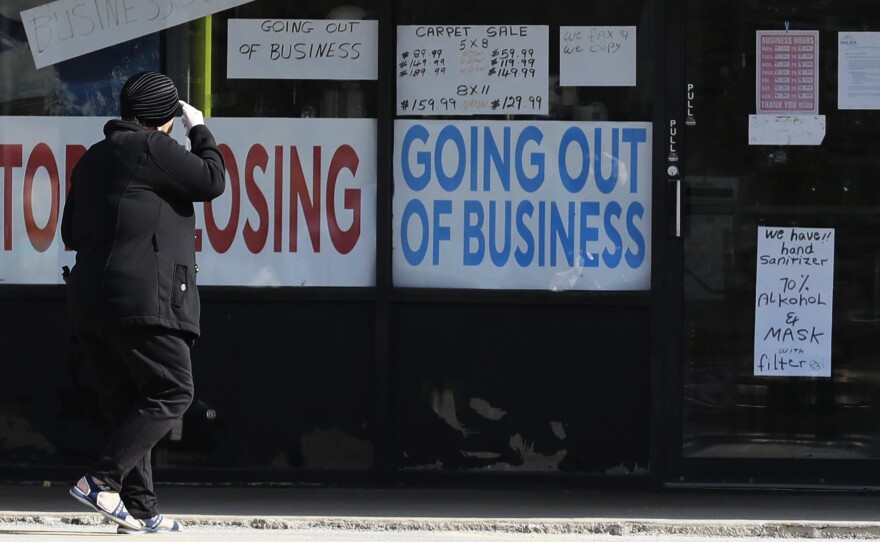 A woman looks at signs at a store in Niles, Ill., on May 13. Shutdowns related to the coronavirus pandemic have left tens of millions out of work.