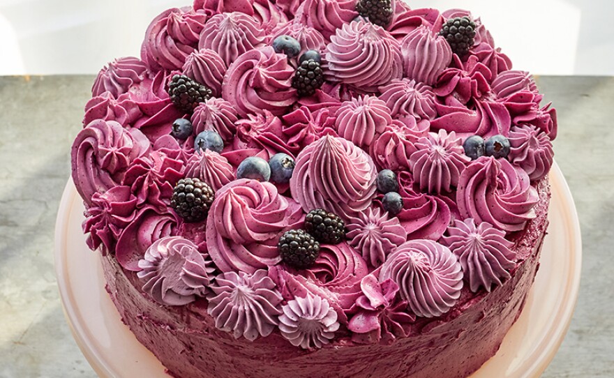 A berry layer cake covered in colorful swirls of Swiss meringue buttercream