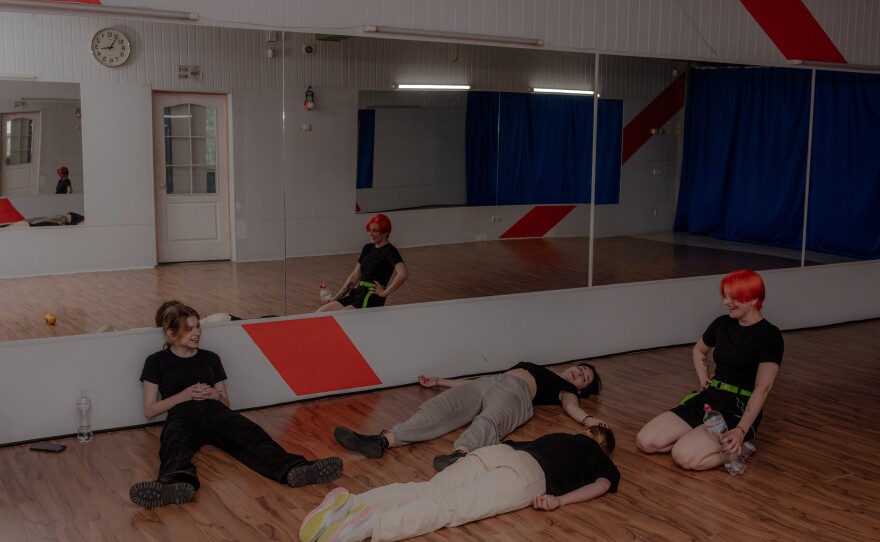 Members of the Phantom Blue dance squad take a break resting on the floor after rehearsal.