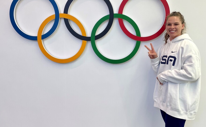 Kelly Curtis stands next to the Olympic rings. She's competing in the skeleton competition at the Beijing Olympics.