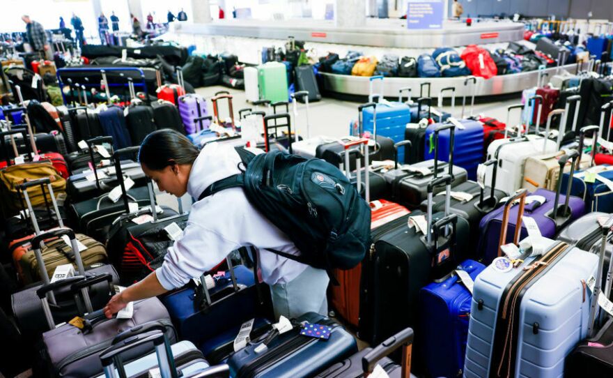 Pristine Floyde searches for a friend's suitcase in a baggage holding area for Southwest Airlines at Denver International Airport in December 2022.