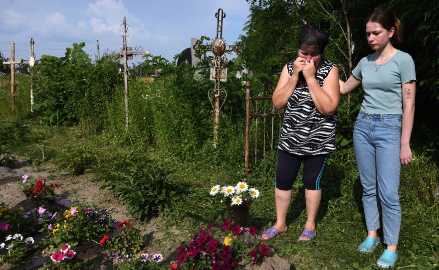 Oksana and Anya Breus visit Oleksandr's grave four months after he was killed.