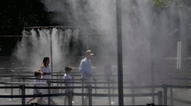 A family walks through a cooling water spray at the Eiffel Tower in Paris, Sunday, June 21, 2026.
