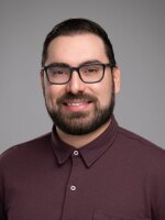 Man smiling with dark hair and glasses