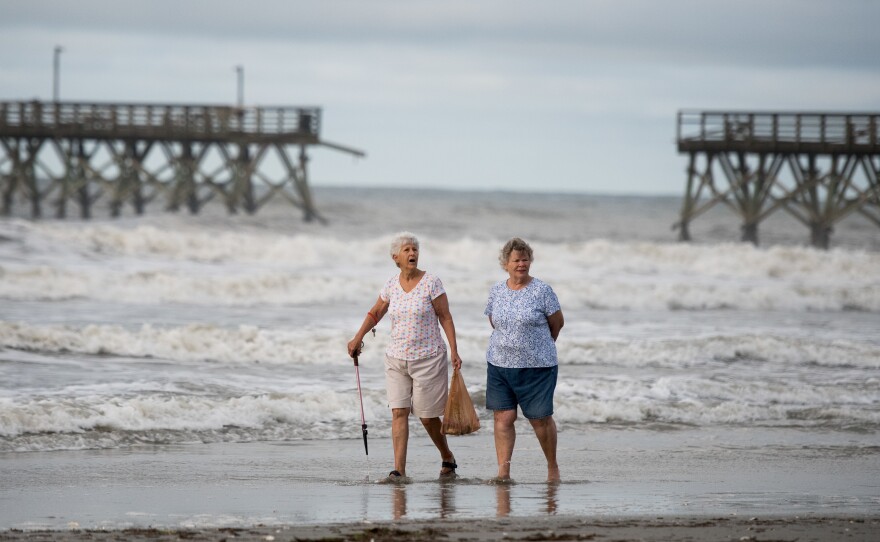 Mary McCants, left, and Amy Garrett walk near a damaged pier the morning after Hurricane Isaias came through late Monday night in North Myrtle Beach, S.C. Hurricane Isaias was downgraded to a tropical storm on Tuesday after making landfall overnight as a Category 1 hurricane.