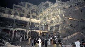 Pakistani police gather beside the destroyed five-star Pearl Continental Hotel in Peshawar, reduced to concrete rubble and twisted steel following Tuesday's bombing. 