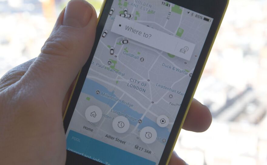 A man holds a smartphone showing the Uber app in London. In September, London transport authorities announced they would not renew Uber's license to operate in the city for safety reasons; on Friday, Uber lost an appeal of a British tribunal decision that its drivers are workers who deserve legal protections.