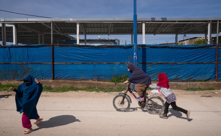 Children ride a bicycle and play in the Roj camp in a Kurdish-held territory in northeast Syria in March. The detention camp houses wives and children of ISIS members.