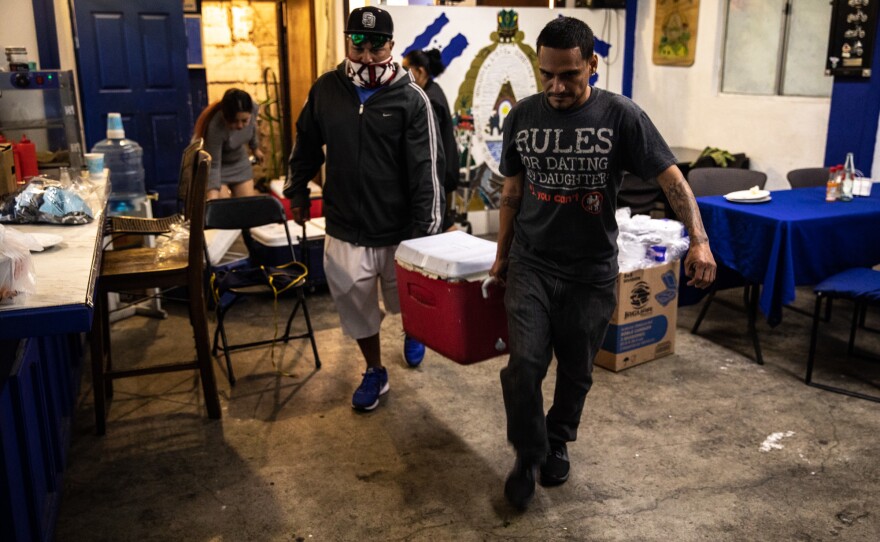 Friends come help the restaurant load coolers filled with stew onto a truck. Customers, employees and the owners, all of whom are Honduran, volunteer their time to help feed the thousands of migrants.