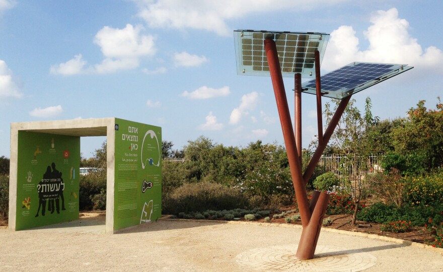 A solar power tree, invented by Michael Lasry, stands at the edge of natural greenery.