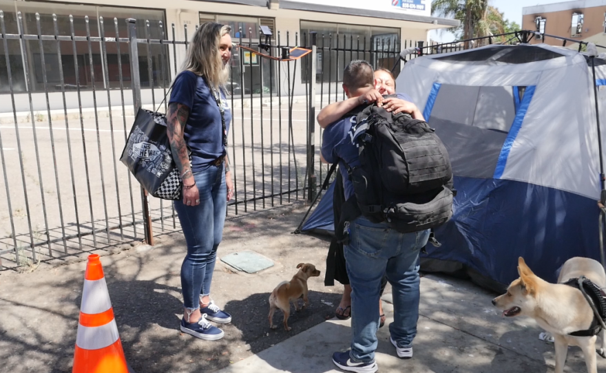 Father Joe's Villages Street Health Team supervisor Jennifer Wilkens, left, looks on as outreach worker Michelle LeFever hugs an unsheltered client in downtown San Diego, on Aug. 1, 2023.