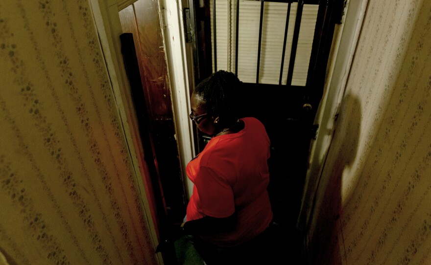 Theresa Bonham makes her way down the stairs to the basement where she had to remove waterlogged wood paneling, a bar and flooring.